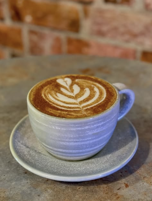 Handcrafted latte art in a ceramic cup against an exposed brick wall